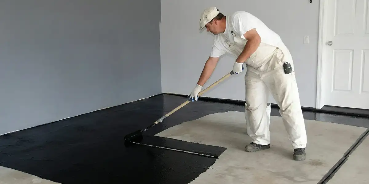 basement waterproofing professional applying waterproof coating to protect a basement floor in Bloomington, IN